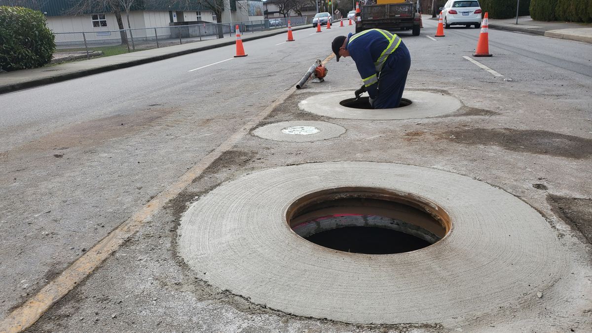 Finished manhole with a clean round concrete collar set flush in the road