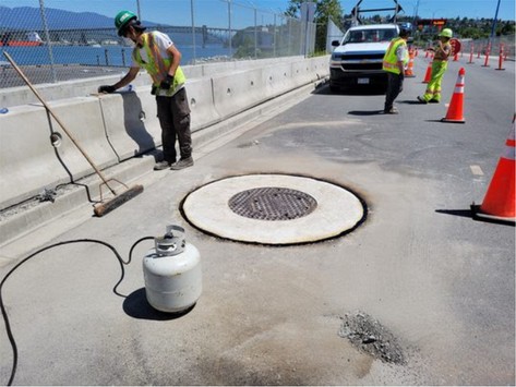 Finished concrete collar around the manhole, with the crew sweeping up
